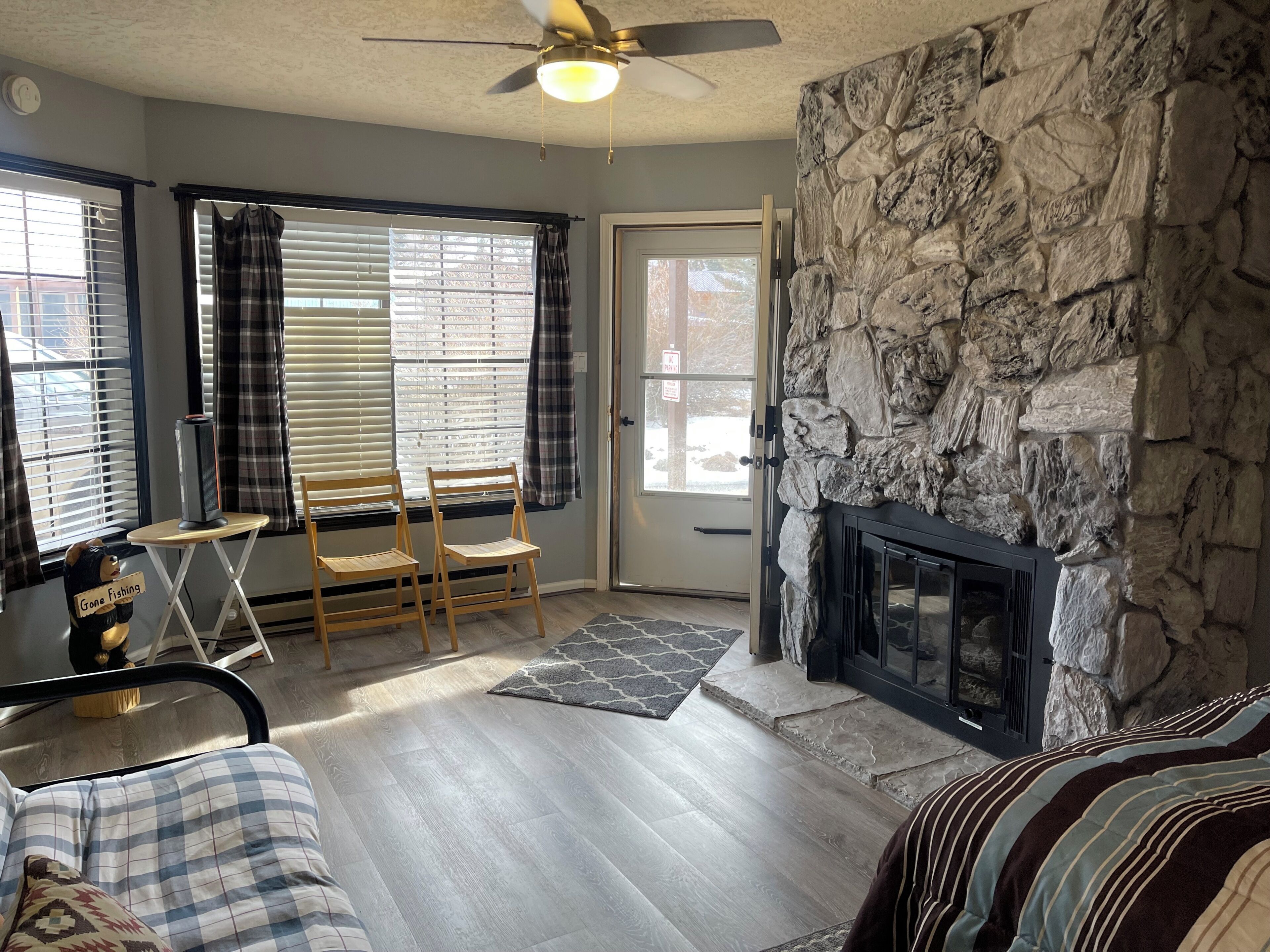 A living room with a stone wall, a fireplace, and a ceiling fan.