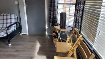 A room with a bed, a desk, a chair, and a window with blinds.