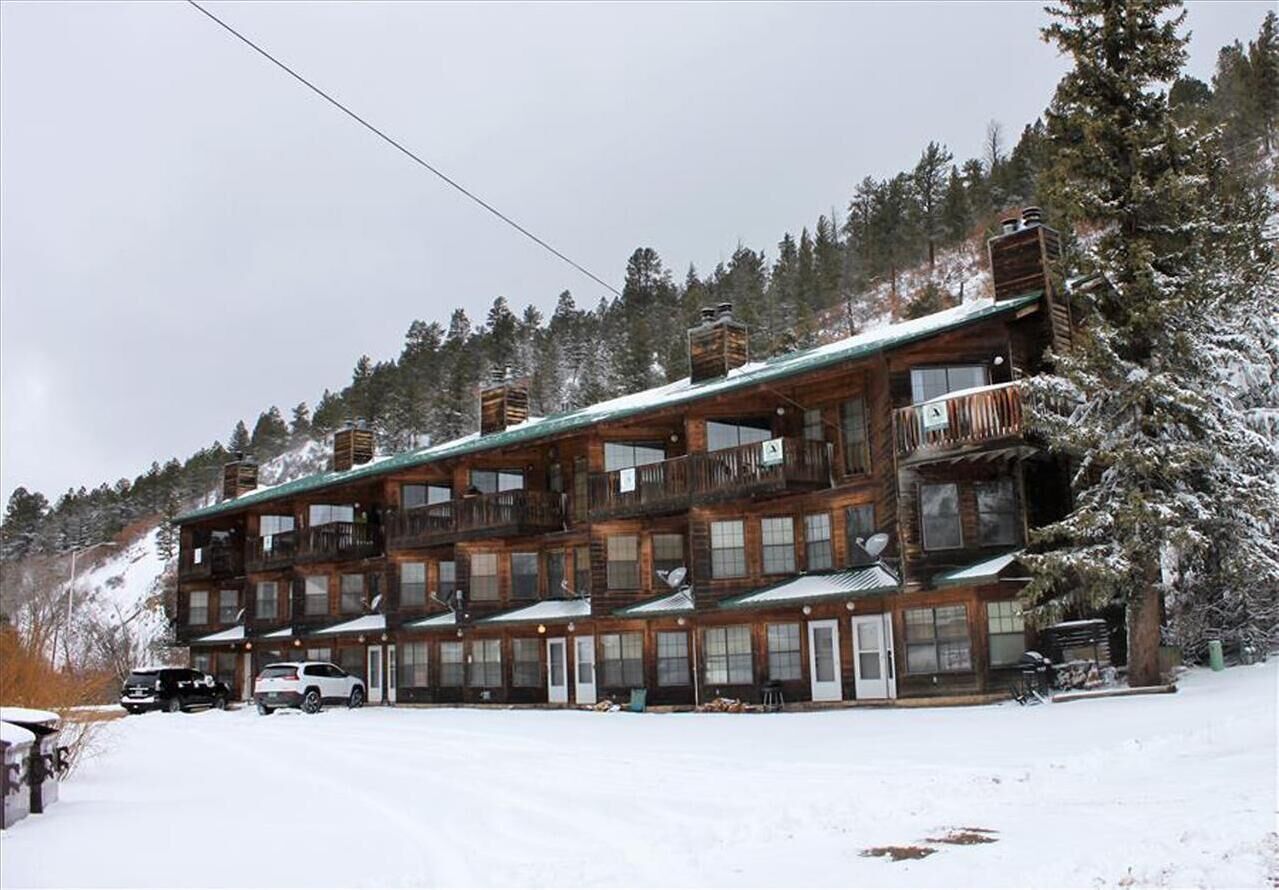 A multi-story lodge with balconies and a ski slope in the background.