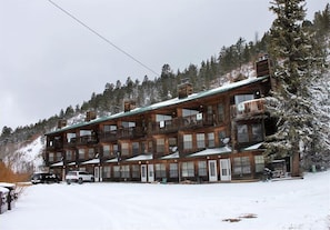 A multi-story lodge with balconies and a ski slope in the background.