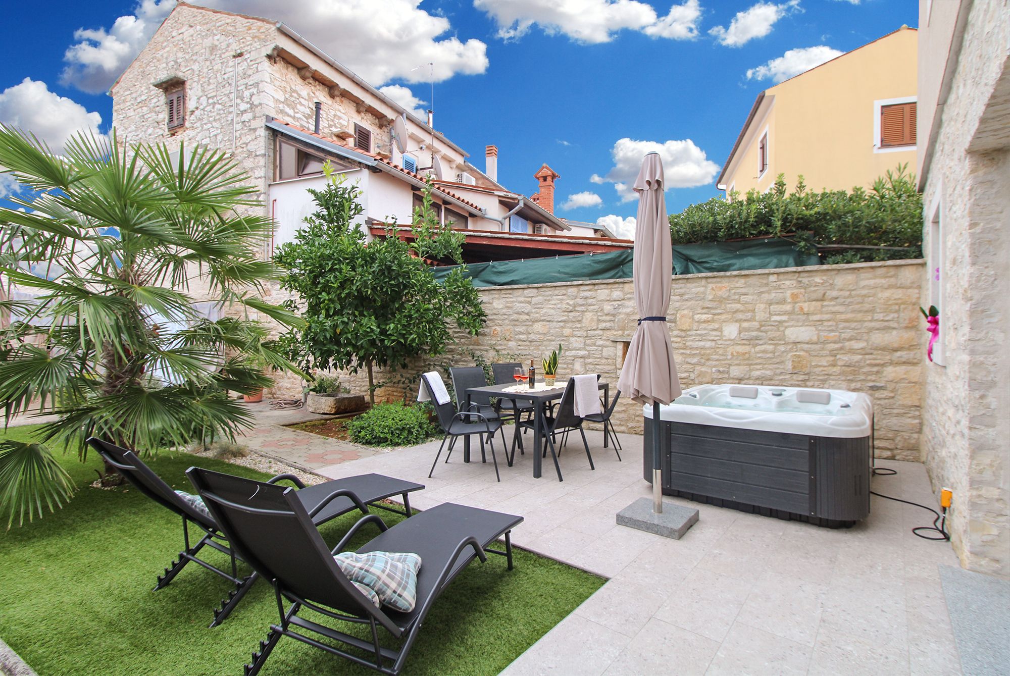 Eine Außenpatio mit Whirlpool, Liegestühlen und einem Tisch mit Stühlen.