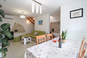 A dining area with a table set for two, a green sofa, and a stone wall. - House 1765/19674 (Istria - Peroj), 1000m from the beach (Peroj)