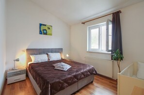 A bedroom with a bed, bedside table, lamp, window, radiator, and a painting on the wall. - House 1765/19674 (Istria - Peroj), 1000m from the beach (Peroj)