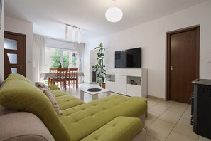 Un salon comprenant un canapé, un téléviseur et un coin repas avec une table et des chaises.