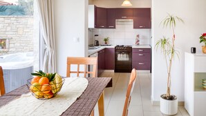 A modern kitchen with purple cabinets, a built-in oven, and a dining area with a table set for two. - House 1765/19674 (Istria - Peroj), 1000m from the beach (Peroj)