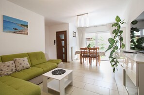 A living room with a green sofa, a white coffee table, and a dining area with wooden chairs and a table. - House 1765/19674 (Istria - Peroj), 1000m from the beach (Peroj)