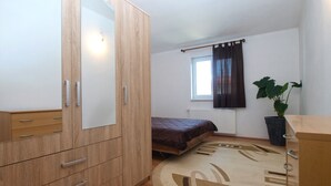 A bedroom with a wooden wardrobe, a bed, a window with curtains, and a potted plant. - House 1765/19674 (Istria - Peroj), 1000m from the beach (Peroj)