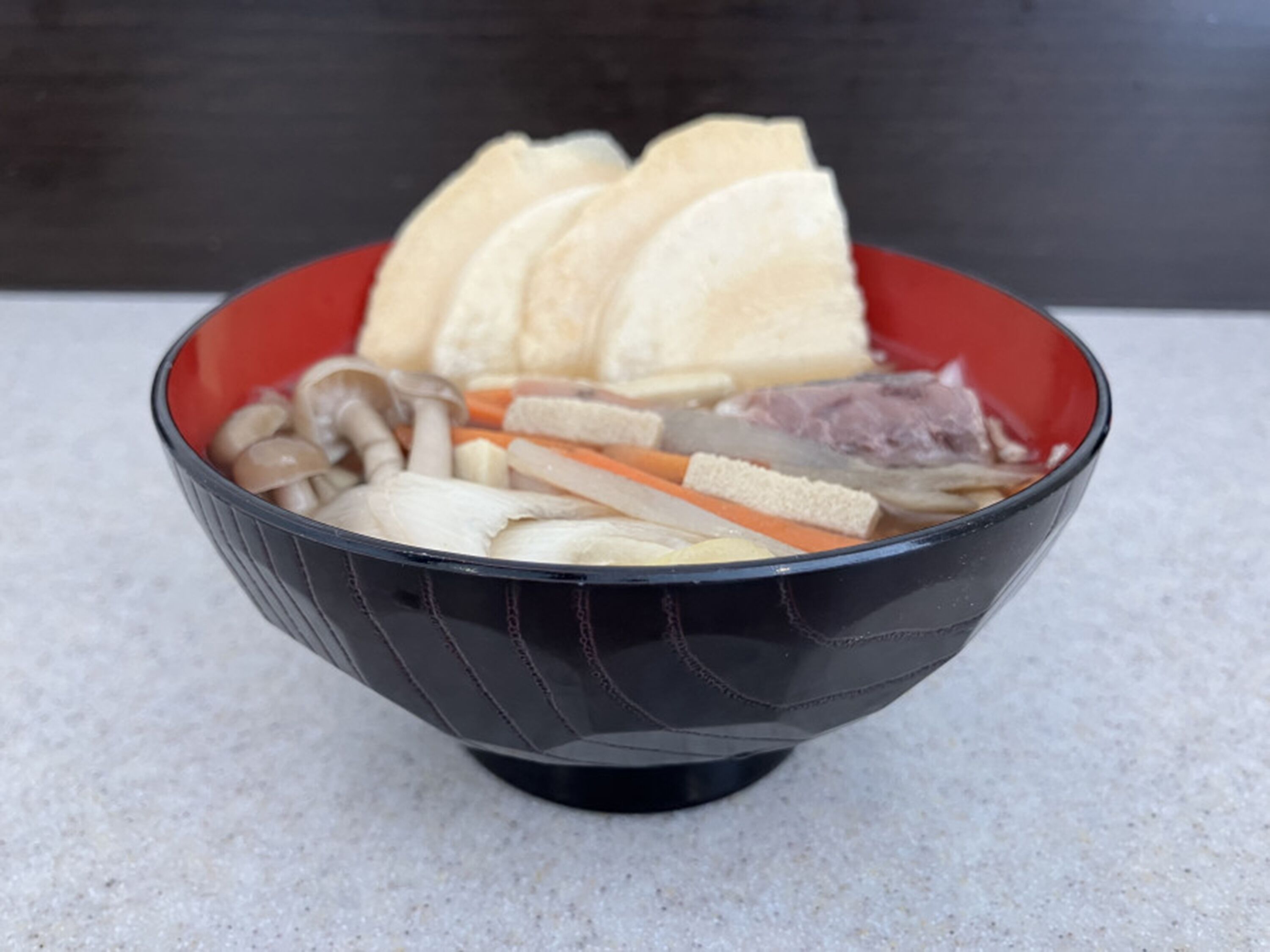 A bowl containing various food items like tofu, mushrooms, and carrots.