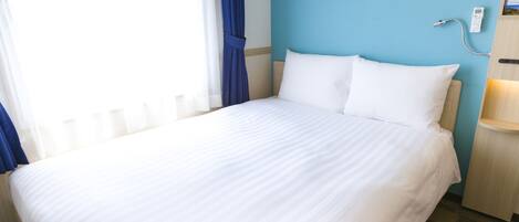 A hotel room with a large bed, a bedside table with a lamp, a wall clock, and a window with curtains.