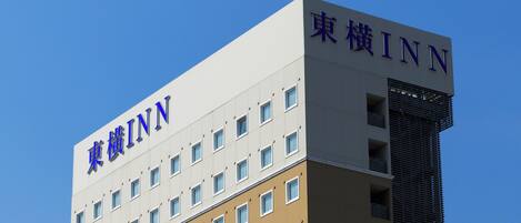 Un edificio de varios pisos con el letrero "東横INN" que indica que es un hotel.