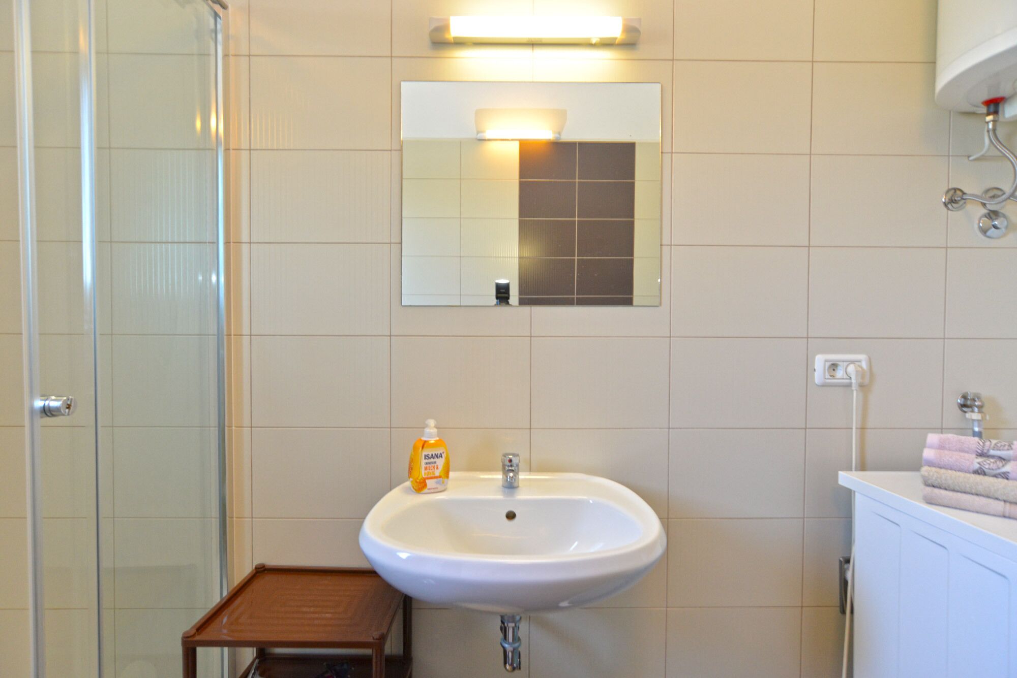 Un bagno con lavandino, specchio e un piccolo sgabello di legno.