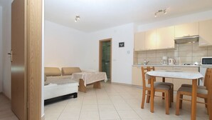 A compact living space with a kitchenette, a dining area with a table and chairs, a sofa, and a bed. - Apartment 1774/20435 (Istria - Liznjan), 1000m from the beach (Liznjan)