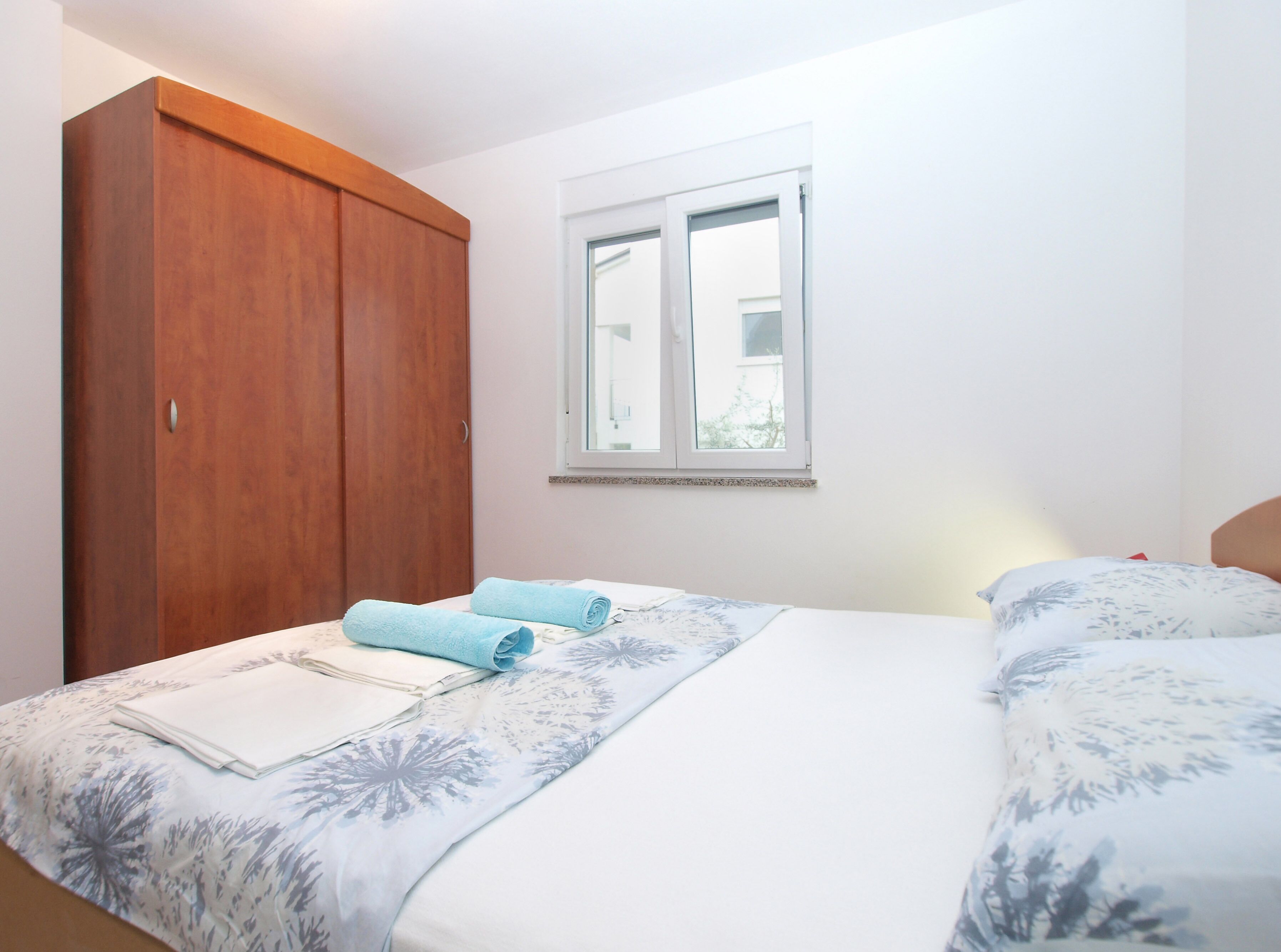 A bedroom with a bed, a wooden wardrobe, and a window. - Apartment 1774/20435 (Istria - Liznjan), 1000m from the beach (Liznjan)