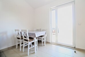 A dining area with a table and chairs, a sliding glass door, and a tiled floor.