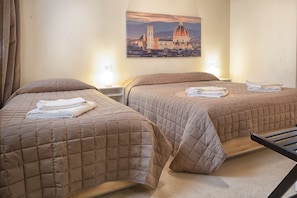 A hotel room with two beds, each with a brown quilted bedspread and neatly folded towels.
