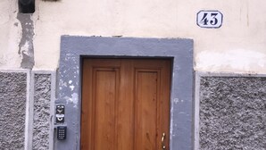 Uma porta de madeira com fechadura eletrônica, uma placa com o número 43 acima dela e uma parede texturizada com tinta descascada.