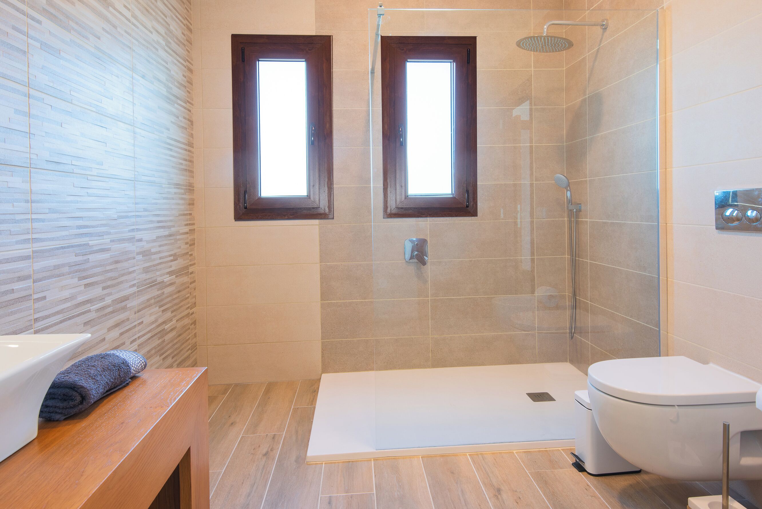 Une salle de bain moderne équipée d’une douche, de toilettes et d’un banc.