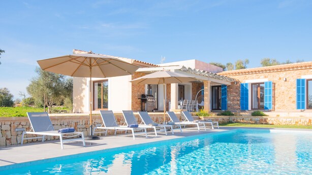 A swimming pool with lounge chairs and umbrellas, a stone building with blue shutters, and a clear blue sky. - Bona Vista with private pool, A/C, table tennis, WiFi, quiet location (Felanitx)