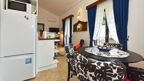 A compact kitchen with a microwave, refrigerator, and a dining area with patterned chairs and a table. - Apartment 1787/20945 (Istria - Barbariga), 1500m from the beach (Barbariga)