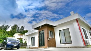 A modern two-story house with a flat roof, large windows, and a visible garage. - White House (Onna)