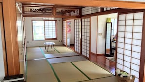 A traditional Japanese room with tatami flooring, sliding doors, and a small table. - White House (Onna)