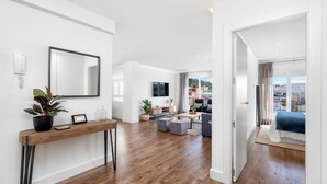 Una sala de estar moderna con suelo de madera, un sofá, una mesa de centro y un televisor.