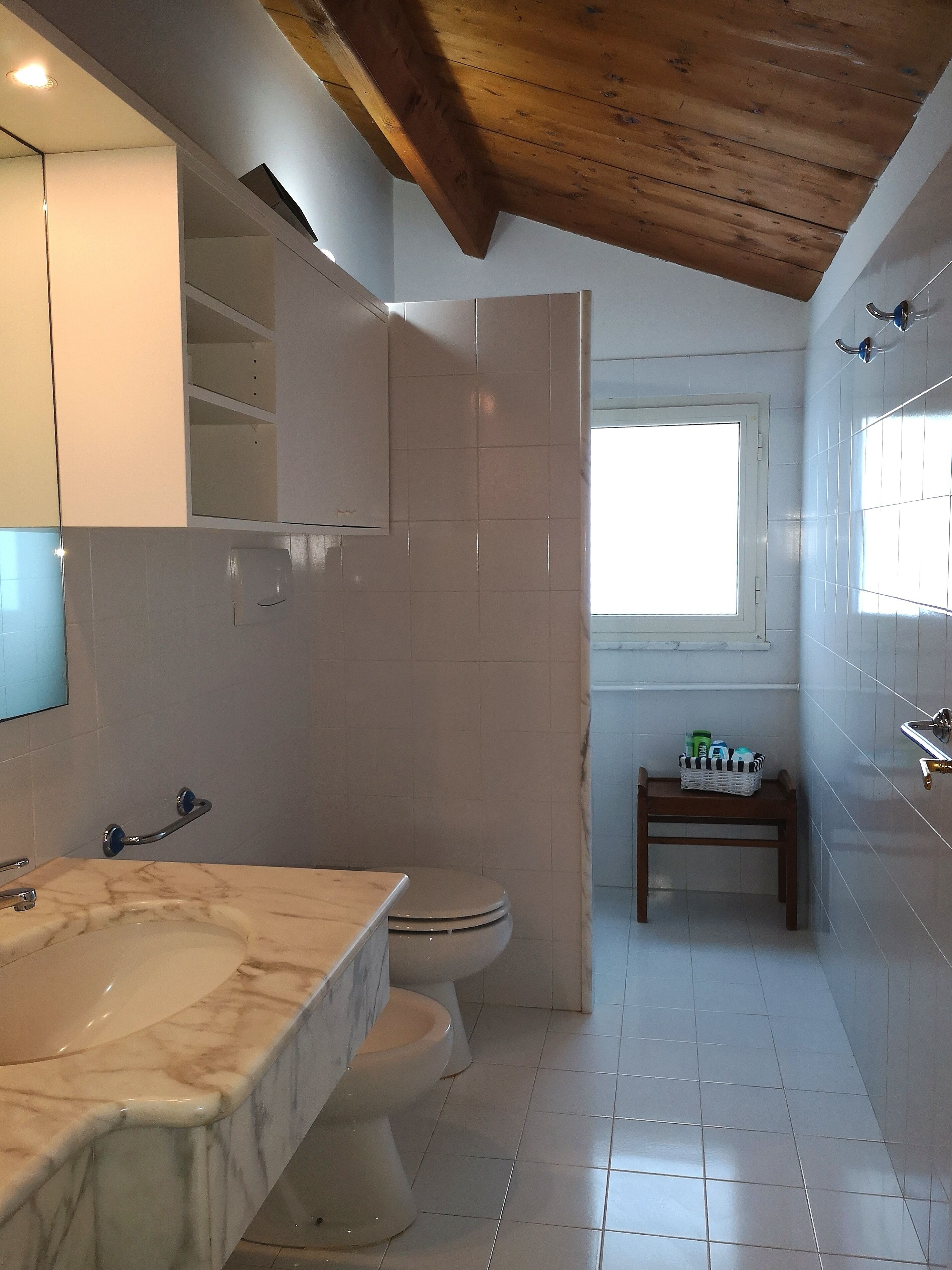 Ein Badezimmer mit Marmorwaschbecken, Toilette und Fenster.