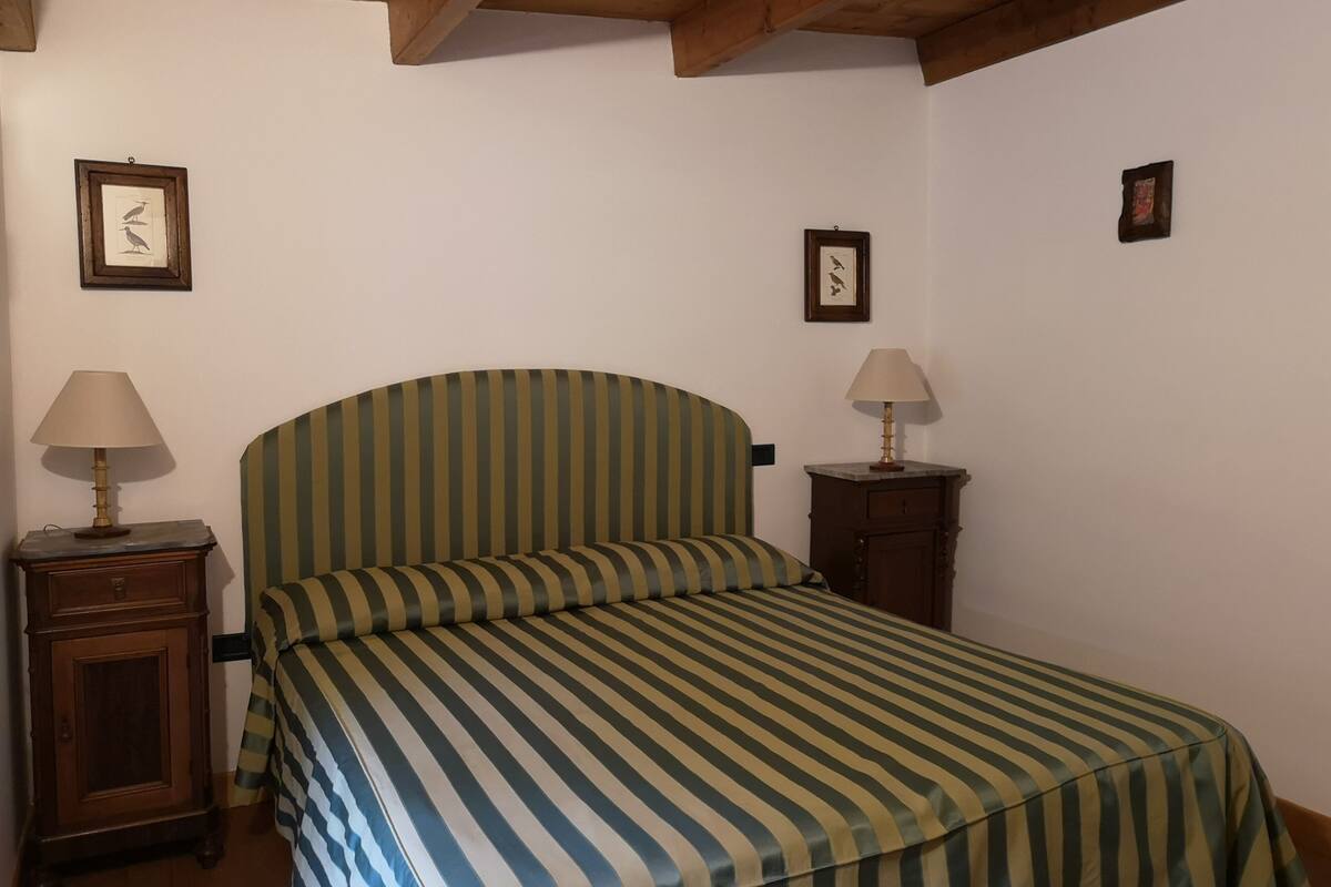 Une chambre comprenant un lit, deux tables de chevet et deux lampes fixées au mur.