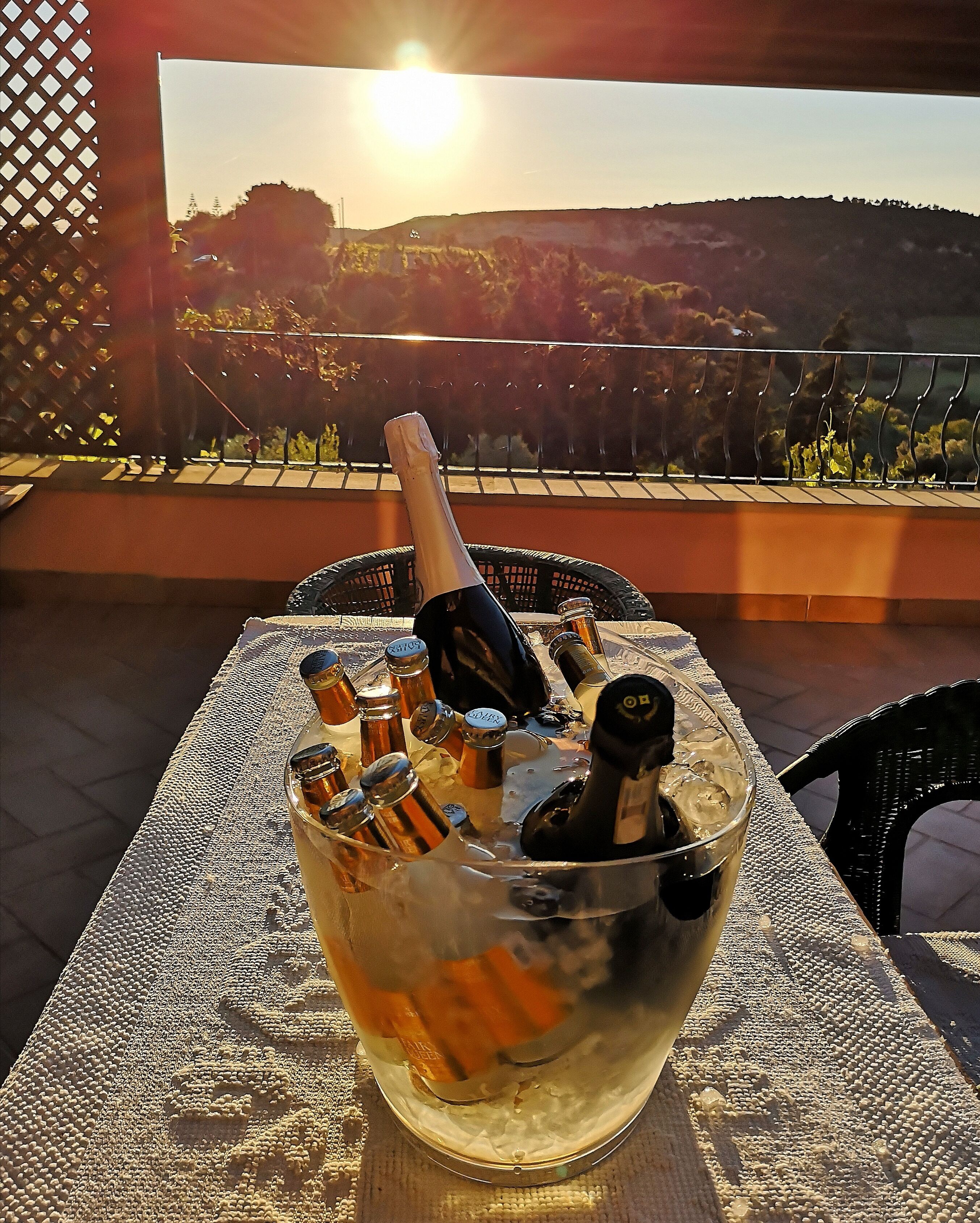 Un tavolo con una bottiglia di champagne, ghiaccio e bicchieri, su un balcone con vista panoramica.