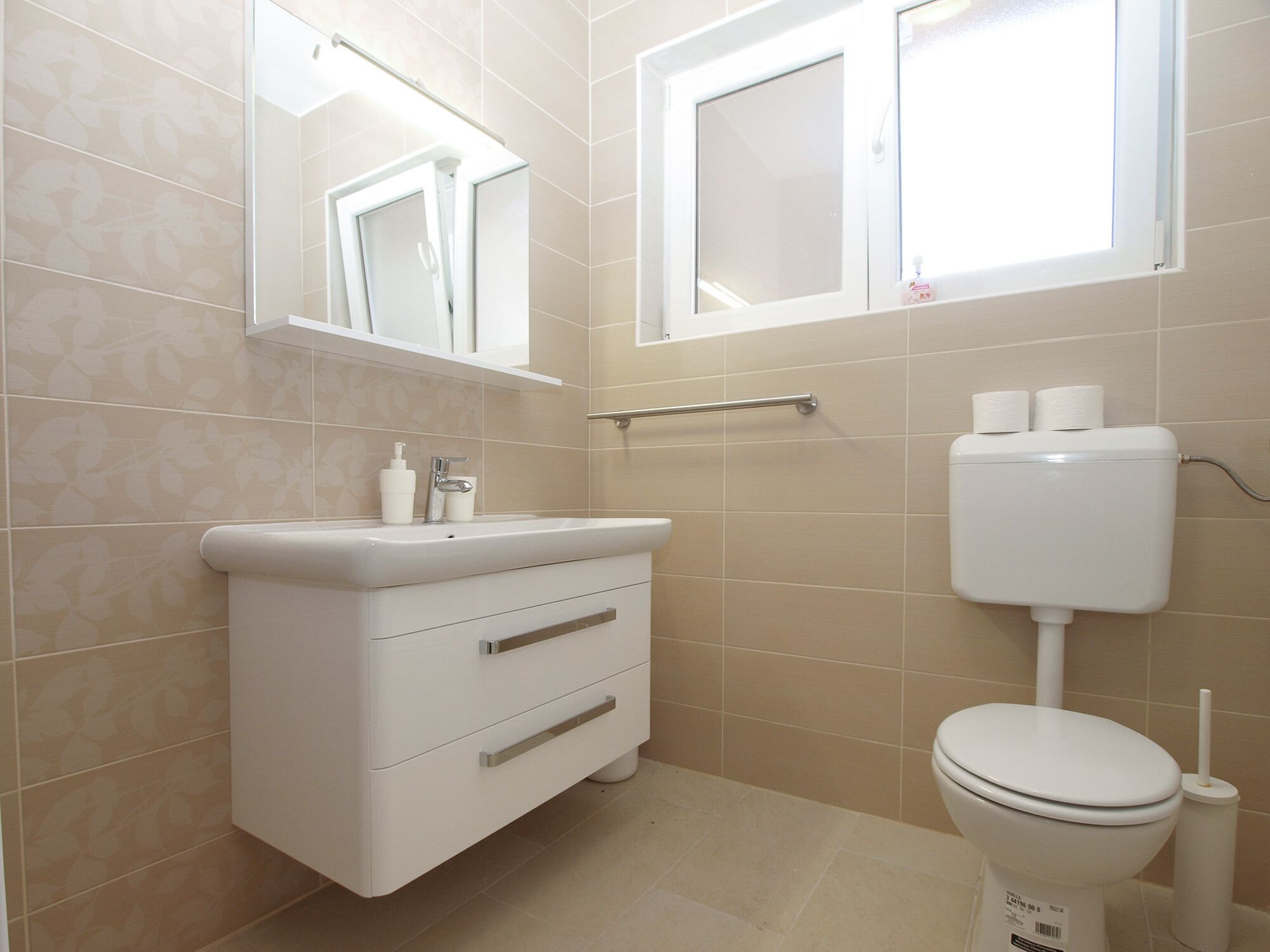 A bathroom with a white sink, mirror, and toilet.