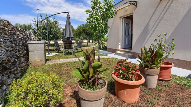 A patio with outdoor furniture, potted plants, a stone wall, and a building with a door and window. - Studio apartment 1805/21278 (Istria - Peroj), 700m from the beach (Peroj)
