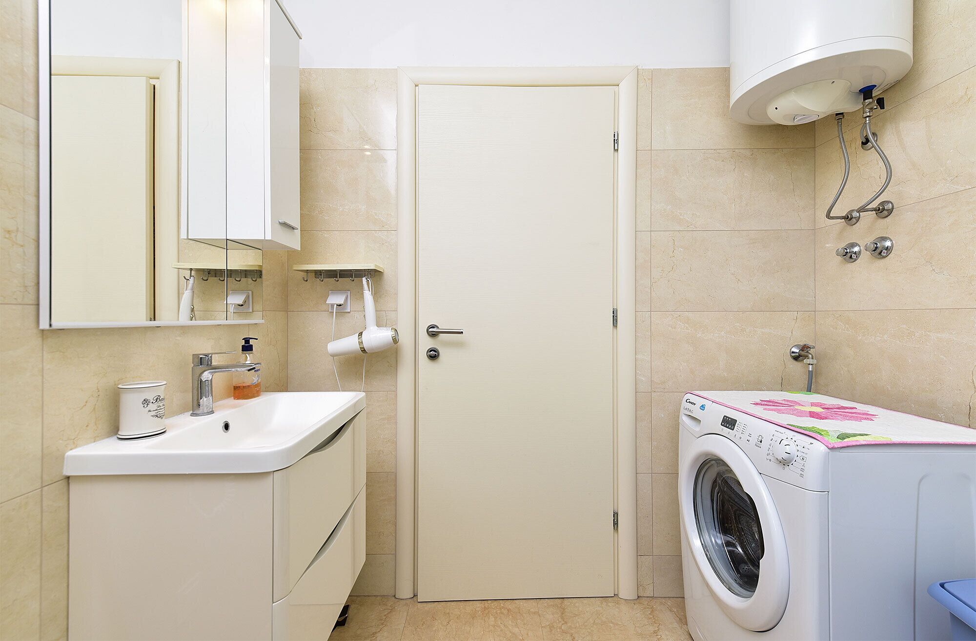 Un baño con lavamanos, espejo, secador de pelo y lavadora.