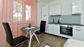 A compact kitchen with white cabinets, a black countertop, and a small dining area with two chairs. - Studio apartment 1805/21278 (Istria - Peroj), 700m from the beach (Peroj)