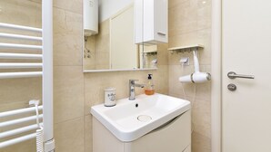 A bathroom with a white sink, a mirror, a towel rack, and a door. - Studio apartment 1805/21278 (Istria - Peroj), 700m from the beach (Peroj)