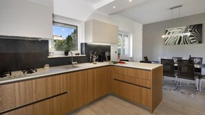 Een moderne keuken met houten kastjes, een ingebouwde kookplaat en een eethoek met barkrukken.
