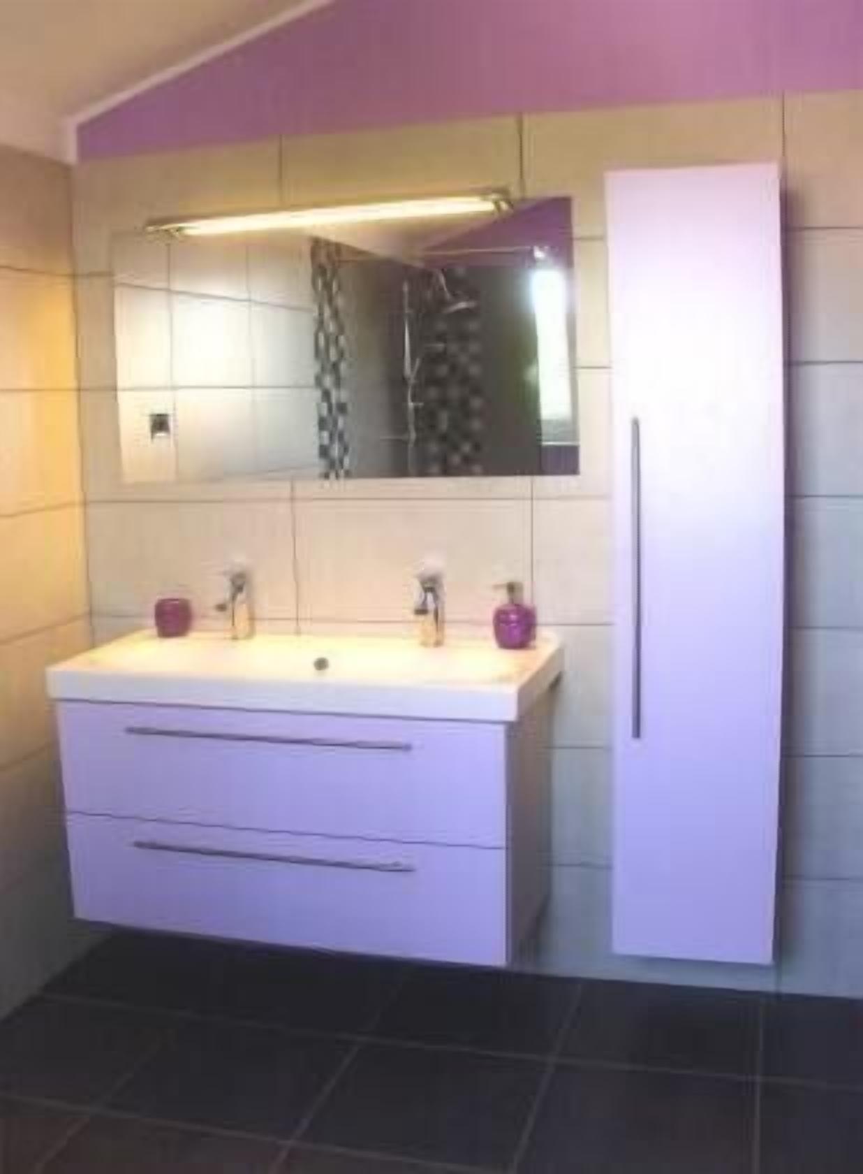 A bathroom with a white vanity, a mirror, and a white cabinet.