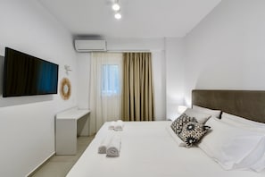 Una habitación de hotel moderna con una cama grande, una mesita de noche, un televisor de pantalla plana en la pared y un equipo de aire acondicionado.