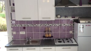 Een keuken met witte kasten, een gasfornuis en een spoelbak.
