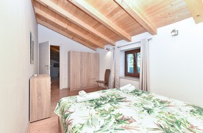 A bedroom with a bed, wooden wardrobe, and a window with curtains.