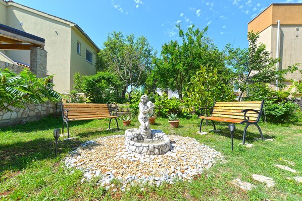 Relax by the serene stone fountain surrounded by lush greenery and tranquil surroundings.