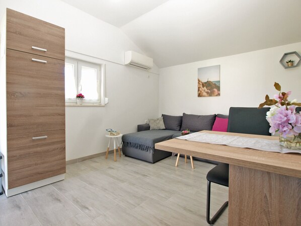 A modern, well-lit room with a wooden wardrobe, a grey sofa, a small side table, and a wooden dining table. - House 1818/21520 (Istria - Pula), 5000m from the beach (Pula)