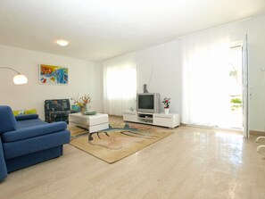 A modern living room with a blue sofa, a flat-screen TV on a white stand, a coffee table, and a colorful rug. - House 1823/21658 (Istria - Vinkuran), 750m from the beach (Vinkuran)