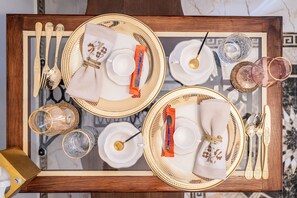 A dining table set with gold-rimmed plates, white napkins, and silverware.