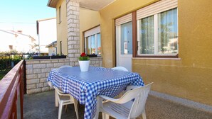 A patio with a checkered table and chairs, a potted plant, and a window with blinds. - Apartment 1827/21673 (Istria - Pula), 4500m from the beach (Pula)