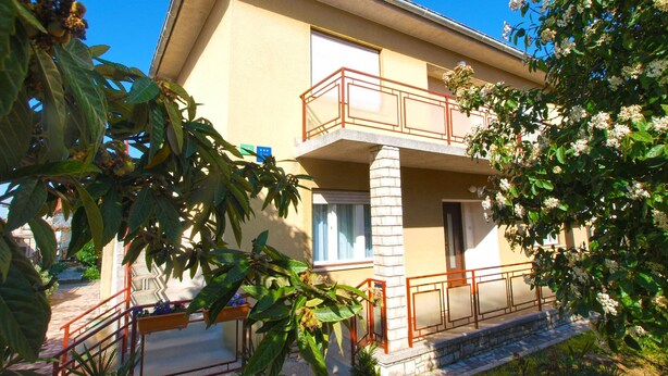 A two-story building with a balcony, a stone pillar, and a garden area with plants and flowers. - Apartment 1827/21673 (Istria - Pula), 4500m from the beach (Pula)