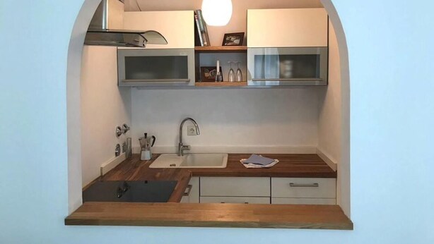 Cocina compacta con encimera de madera, un lavabo y una lámpara colgante.