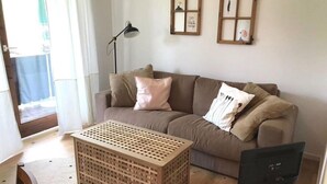 Una sala de estar con una mesa de centro de madera, un sofá, un televisor y una lámpara.