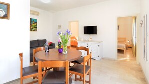 A dining area with a round wooden table and chairs, a sofa, a TV, and a bed in the background. - House 1829/21736 (Istria - Rakalj), 1500m from the beach (Rakalj)