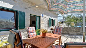 An outdoor seating area with a wooden table and chairs, a potted plant, and a striped umbrella. - House 1829/21736 (Istria - Rakalj), 1500m from the beach (Rakalj)
