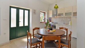 A dining area with a round table, six wooden chairs, a vase with flowers, and a green pendant light. - House 1829/21736 (Istria - Rakalj), 1500m from the beach (Rakalj)